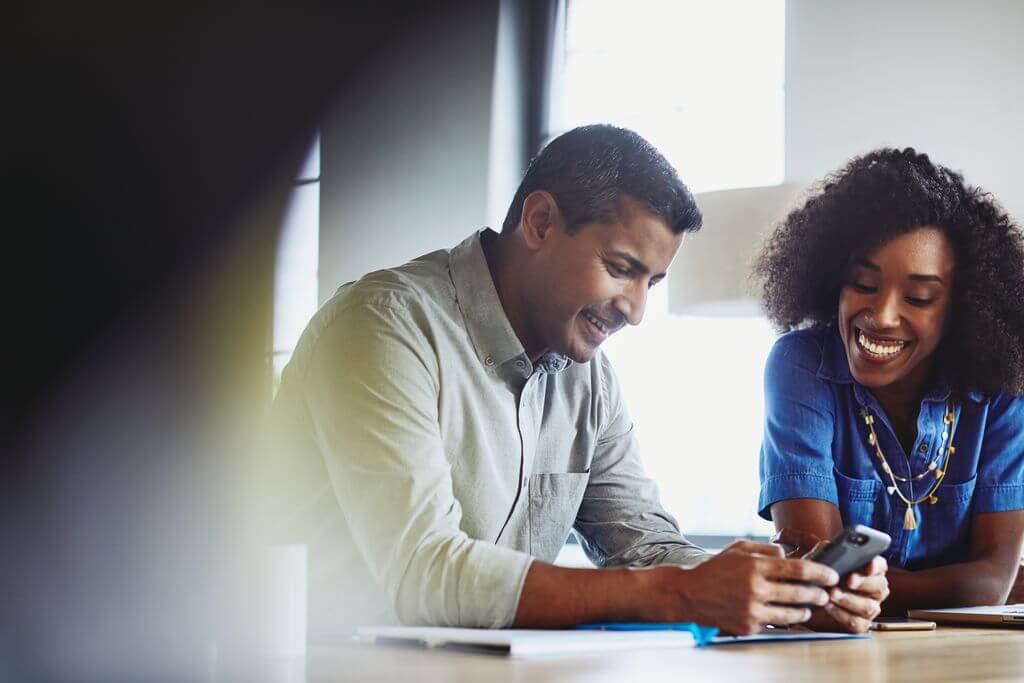 Smiling man and woman looking down at phone